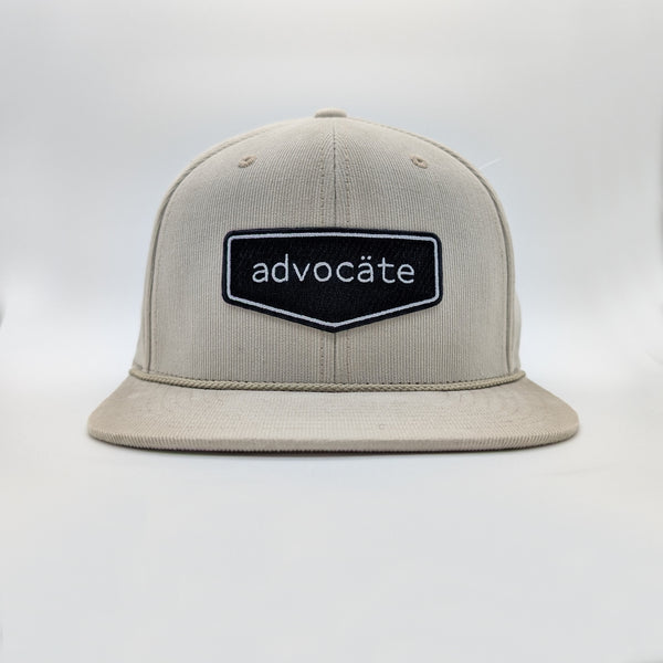 Beige cap with 'advocáte' logo on a white background