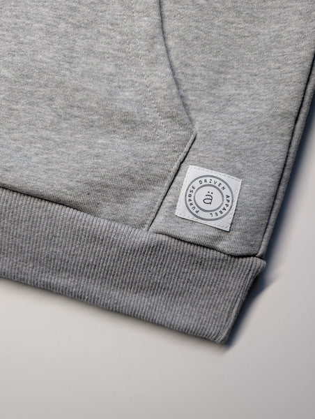 close-up of the purpose hoodie hem by advocäte showing ribbed waistband and woven brand patch on organic cotton fleece